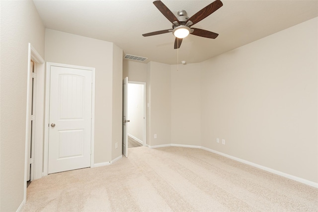 unfurnished bedroom with a ceiling fan, light colored carpet, visible vents, and baseboards