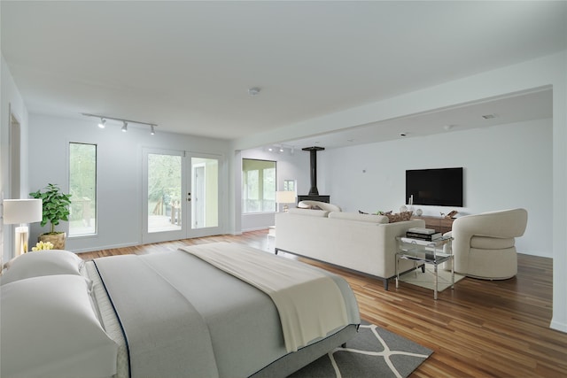 bedroom with french doors, a wood stove, track lighting, wood finished floors, and access to outside