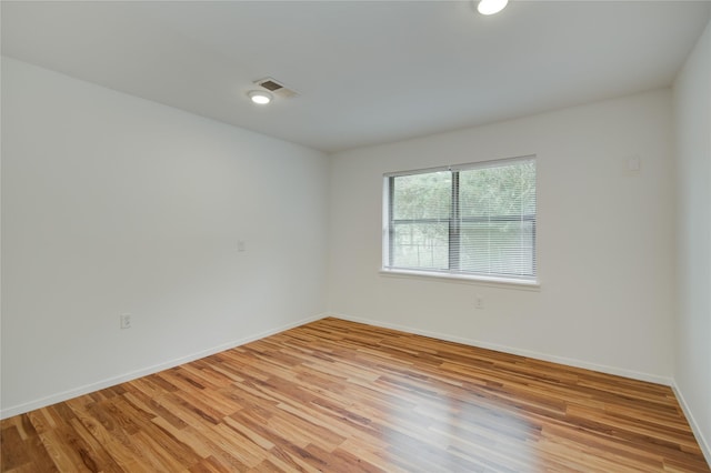 spare room with baseboards, visible vents, and light wood-style floors