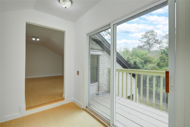 doorway to outside with lofted ceiling, light wood-type flooring, and baseboards