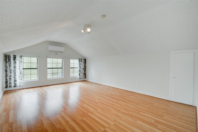 bonus room with a wealth of natural light, lofted ceiling, a wall unit AC, and wood finished floors