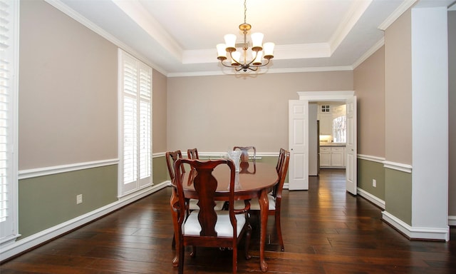 dining space featuring a tray ceiling, dark wood-style flooring, and an inviting chandelier