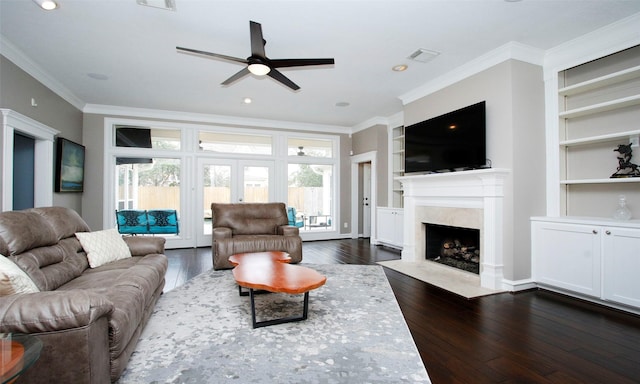 living room with visible vents, built in shelves, ornamental molding, and dark wood finished floors