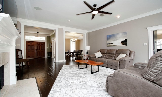 living room featuring visible vents, dark wood finished floors, a premium fireplace, crown molding, and ceiling fan with notable chandelier