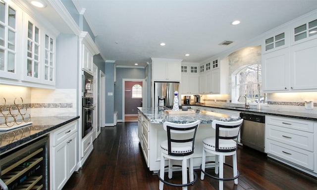 kitchen featuring beverage cooler, a sink, visible vents, white cabinets, and appliances with stainless steel finishes