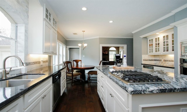 kitchen with dark wood-style floors, stainless steel appliances, white cabinetry, a sink, and dark stone counters