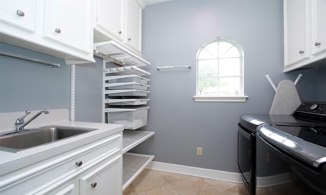 laundry area featuring cabinet space, baseboards, washing machine and dryer, a sink, and light tile patterned flooring