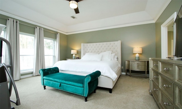 bedroom with a ceiling fan, a tray ceiling, light carpet, and crown molding