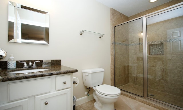 bathroom featuring a stall shower, baseboards, toilet, tile patterned flooring, and vanity