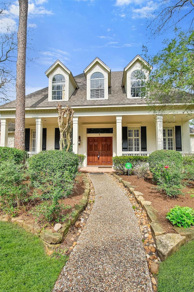 cape cod-style house with a garage, driveway, and a porch