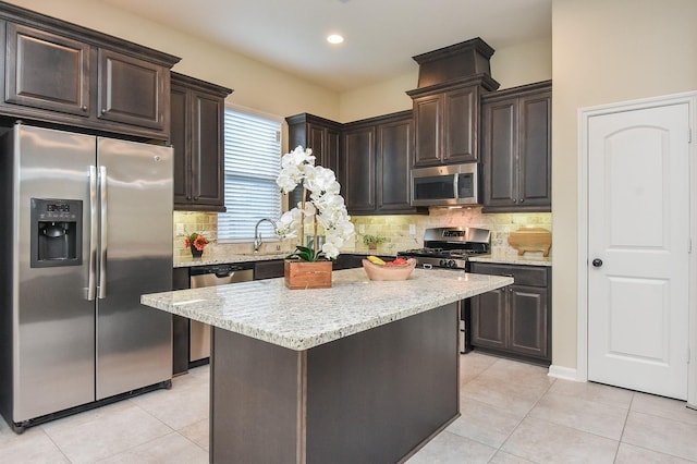 kitchen with dark brown cabinetry, light tile patterned flooring, light stone countertops, and stainless steel appliances