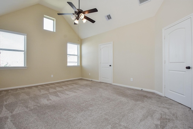 spare room featuring visible vents, light colored carpet, high vaulted ceiling, and ceiling fan