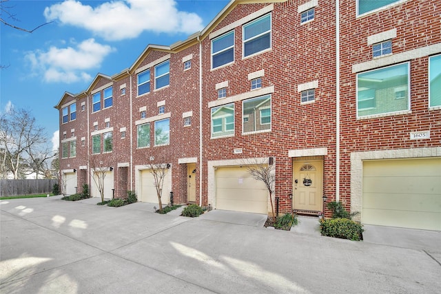 view of building exterior with a garage, driveway, and a residential view