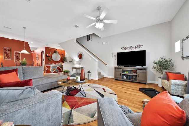 living room featuring visible vents, stairway, a ceiling fan, wood finished floors, and baseboards