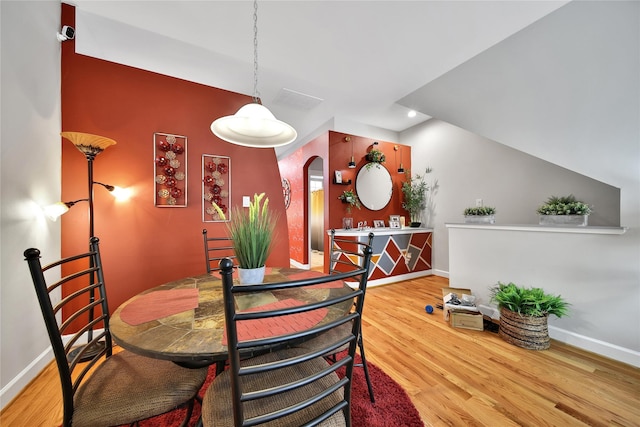 dining area featuring arched walkways, wood finished floors, and baseboards