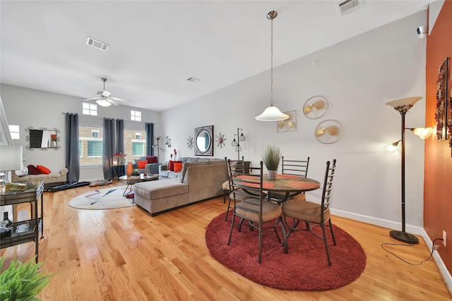 dining space featuring light wood-style flooring, a ceiling fan, visible vents, and baseboards