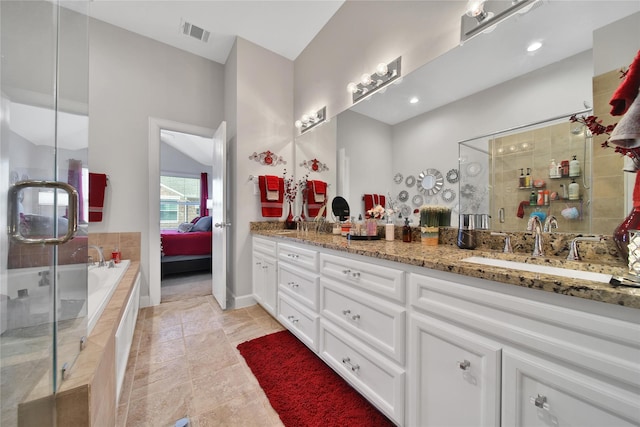 full bathroom with double vanity, a stall shower, a relaxing tiled tub, visible vents, and ensuite bath