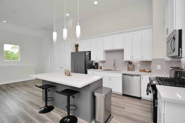 kitchen featuring decorative backsplash, a kitchen island, appliances with stainless steel finishes, a kitchen bar, and a sink