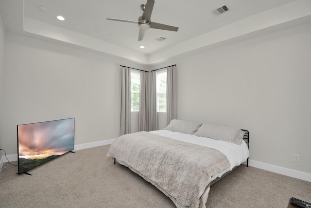 bedroom with light carpet, recessed lighting, a raised ceiling, and baseboards