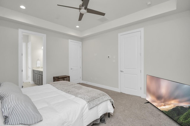 carpeted bedroom featuring baseboards, a tray ceiling, ensuite bathroom, and recessed lighting