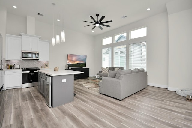 kitchen with tasteful backsplash, a towering ceiling, appliances with stainless steel finishes, open floor plan, and light countertops