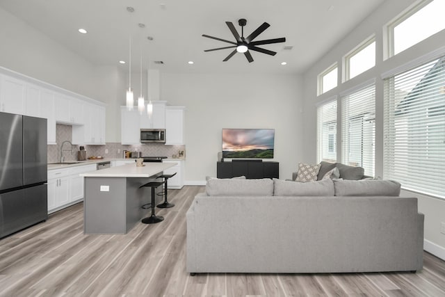 living area with visible vents, baseboards, a high ceiling, light wood-type flooring, and recessed lighting