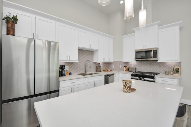 kitchen with stainless steel appliances, backsplash, a sink, and a center island