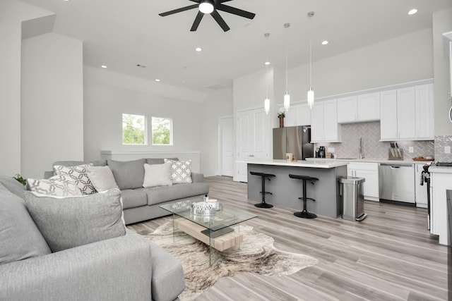 living area featuring light wood finished floors, a high ceiling, a ceiling fan, and recessed lighting