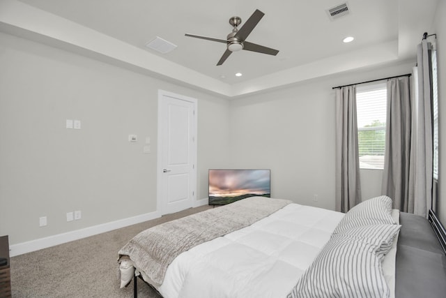 bedroom featuring a tray ceiling, carpet, visible vents, and baseboards