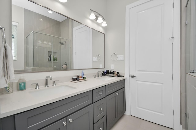 full bath featuring tile patterned flooring, a sink, a shower stall, and double vanity