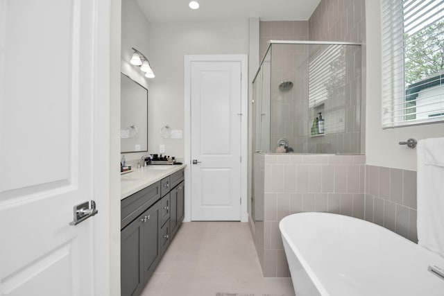 full bath with double vanity, a sink, a shower stall, tile patterned flooring, and a freestanding tub