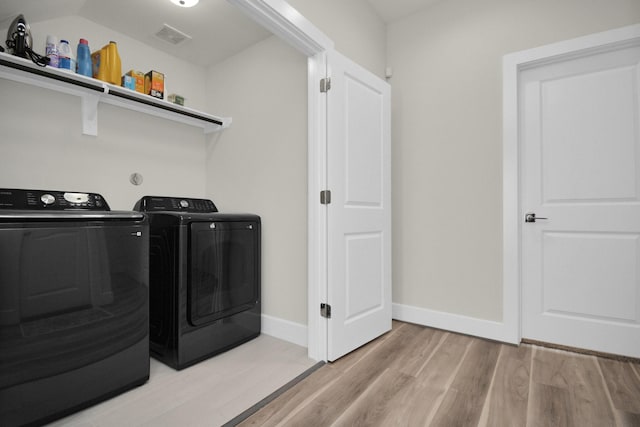 laundry room featuring laundry area, visible vents, baseboards, light wood-style flooring, and washing machine and clothes dryer