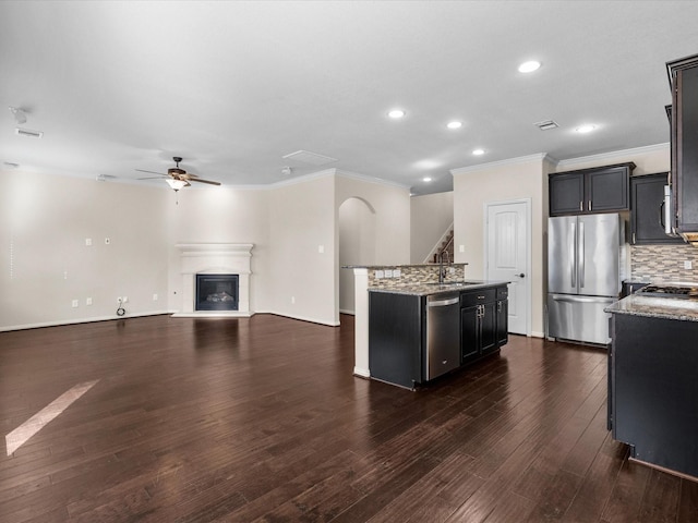 kitchen featuring dark wood-type flooring, a sink, a ceiling fan, appliances with stainless steel finishes, and a glass covered fireplace