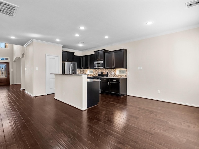 kitchen featuring stainless steel appliances, arched walkways, visible vents, and backsplash