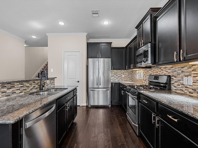 kitchen with visible vents, dark stone counters, stainless steel appliances, dark cabinetry, and a sink