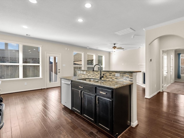 kitchen with dark wood finished floors, decorative backsplash, a sink, dark cabinets, and dishwasher