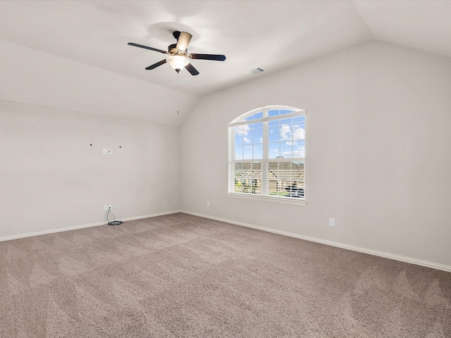 carpeted spare room featuring lofted ceiling, visible vents, a ceiling fan, and baseboards