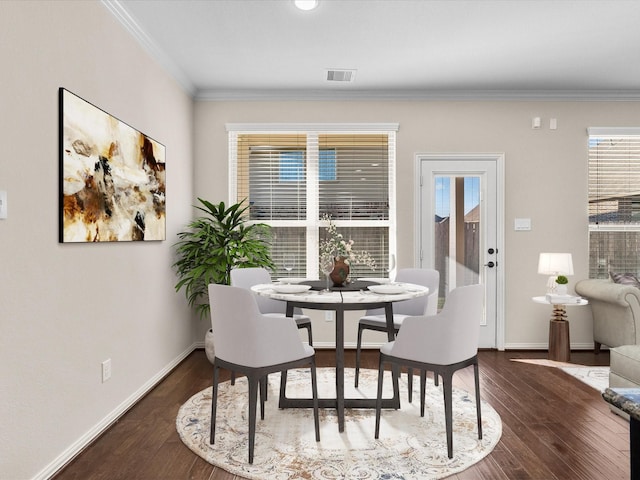 dining room with ornamental molding, wood finished floors, visible vents, and baseboards