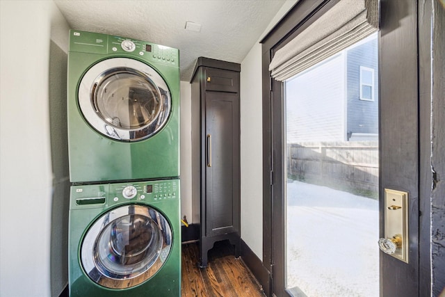 washroom with stacked washer and dryer, laundry area, baseboards, dark wood-type flooring, and a textured ceiling