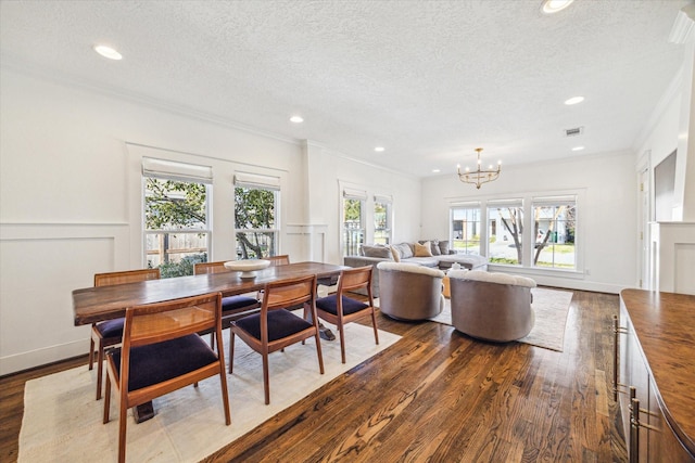 dining space with visible vents, dark wood-style flooring, crown molding, a textured ceiling, and a chandelier