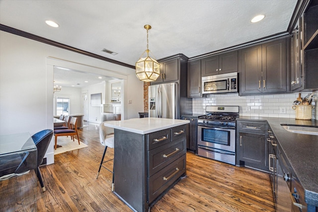 kitchen with stainless steel appliances, visible vents, a kitchen breakfast bar, decorative backsplash, and dark wood finished floors