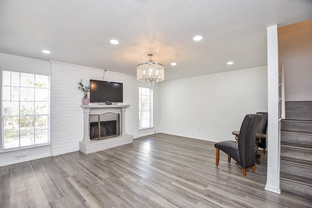 living area featuring stairs, a textured ceiling, a fireplace, and wood finished floors