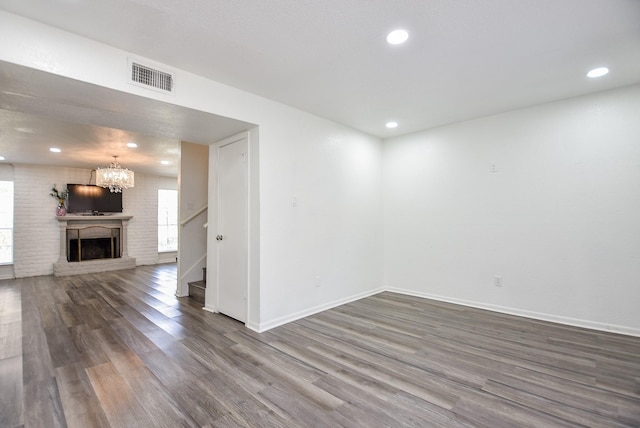 spare room with baseboards, visible vents, a fireplace with raised hearth, stairway, and wood finished floors