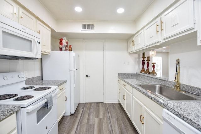 kitchen with white appliances, a sink, visible vents, and white cabinets