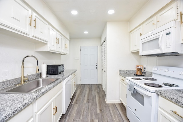 kitchen with white appliances, dark wood-type flooring, a sink, and white cabinetry