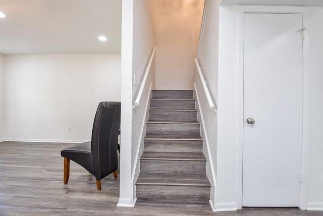 staircase featuring baseboards, wood finished floors, and recessed lighting