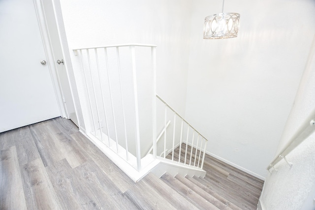 stairs with a chandelier, baseboards, and wood finished floors