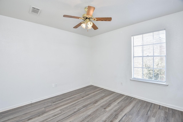 spare room with baseboards, wood finished floors, visible vents, and a healthy amount of sunlight