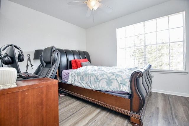 bedroom featuring wood finished floors, a ceiling fan, and baseboards