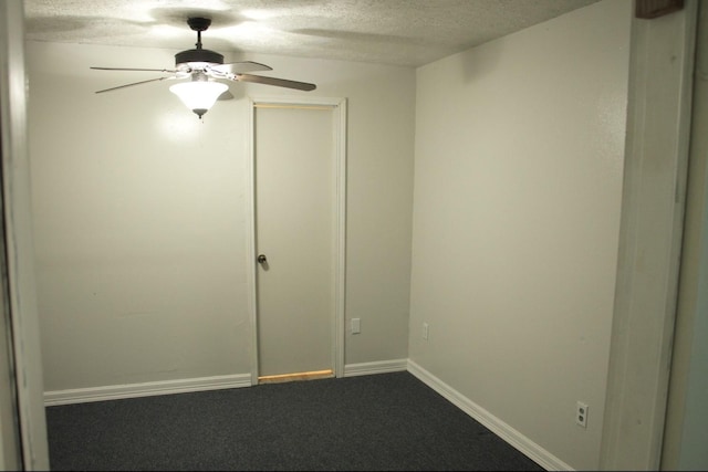 spare room featuring ceiling fan, baseboards, dark colored carpet, and a textured ceiling